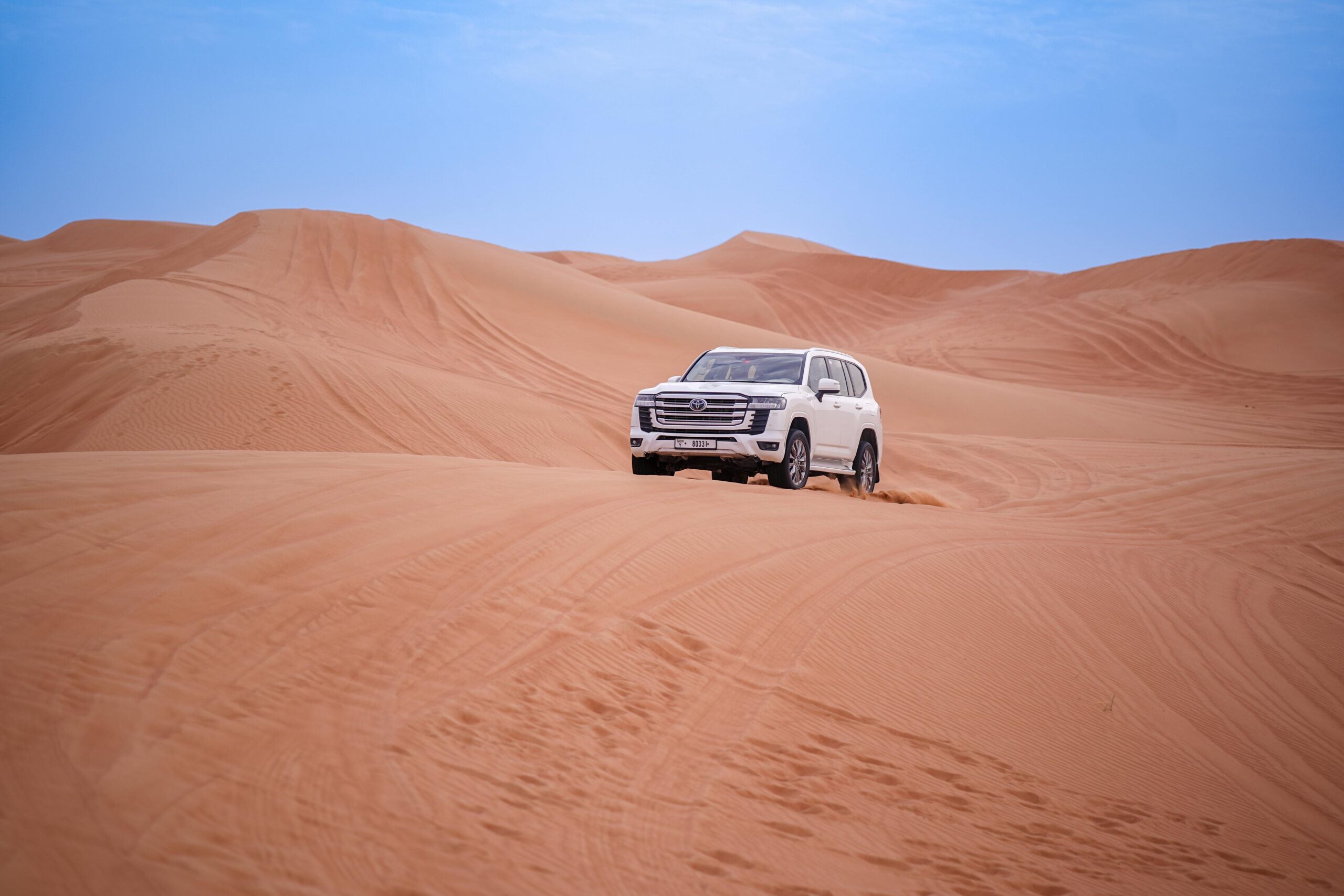 an 4x4 vehicle navigating sand dunes under the soft morning light during a thrilling dune bashing experience in the desert